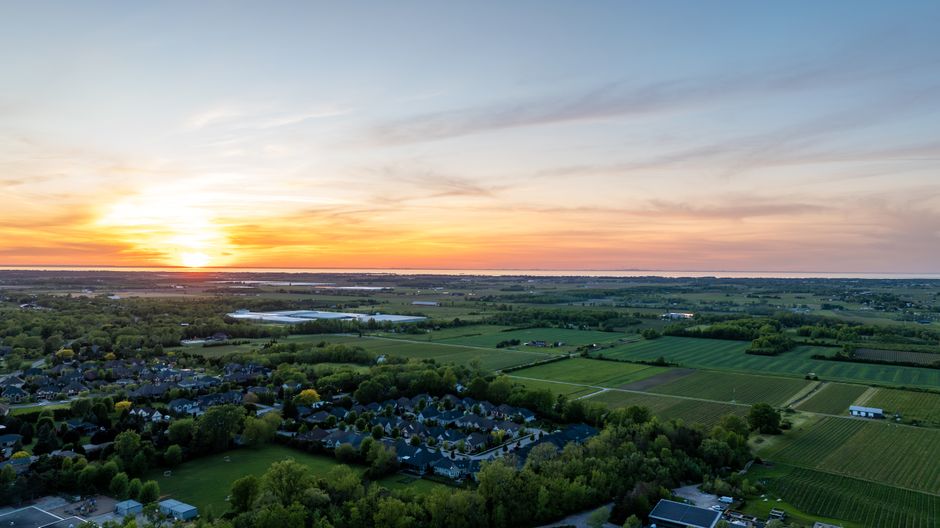 Spectacular Private Tour: Romantic Niagara Falls Helicopter Flight Review 2026 - A breathtaking aerial view of the sunset over Niagara-On-The-Lake with fields and houses.