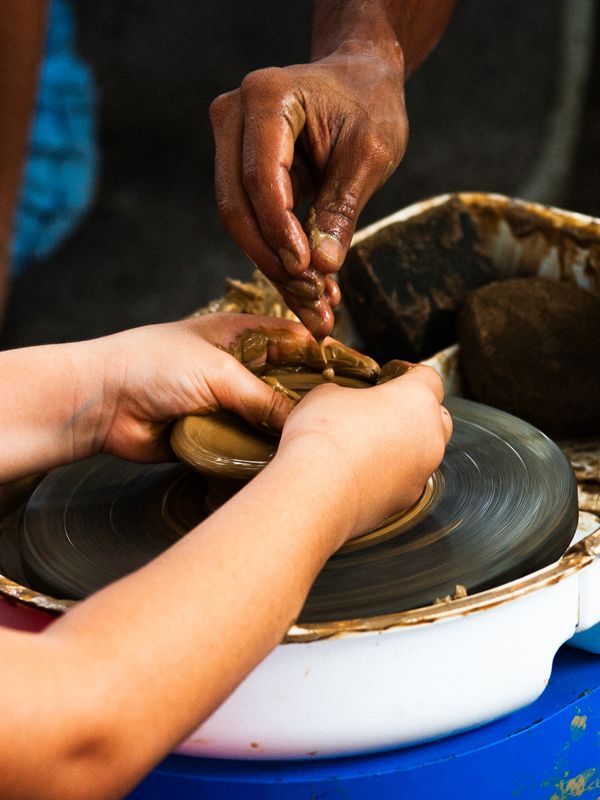 Two pairs of hands shaping clay on a pottery wheel. Photo by Luis Eduardo Lustosa on Pexels.