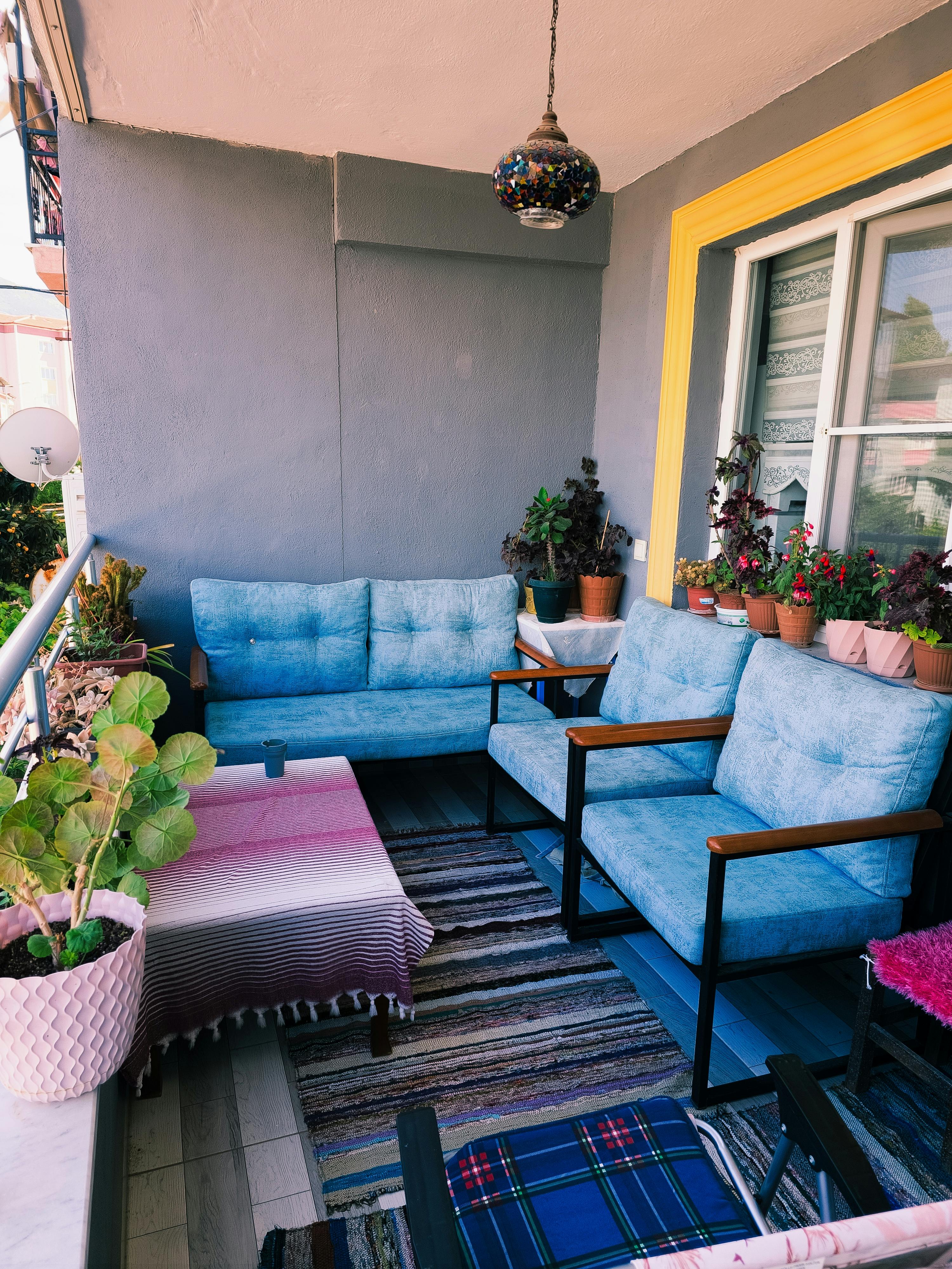 Charming balcony with blue seating, vibrant textiles, and potted plants creating a cozy atmosphere.