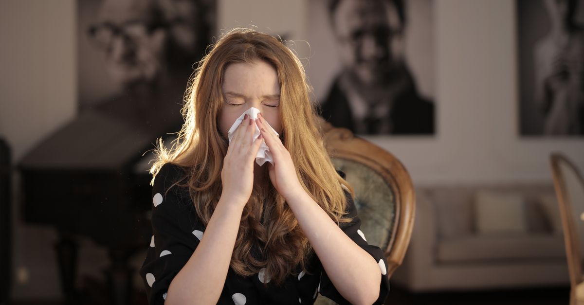 Sick woman wiping her nose with tissue