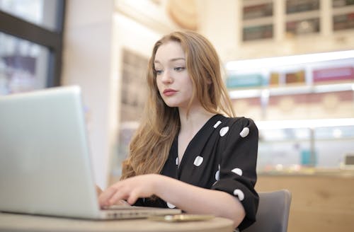 Wanita Berbaju Polka Dots Hitam Putih Menggunakan Laptop Silver