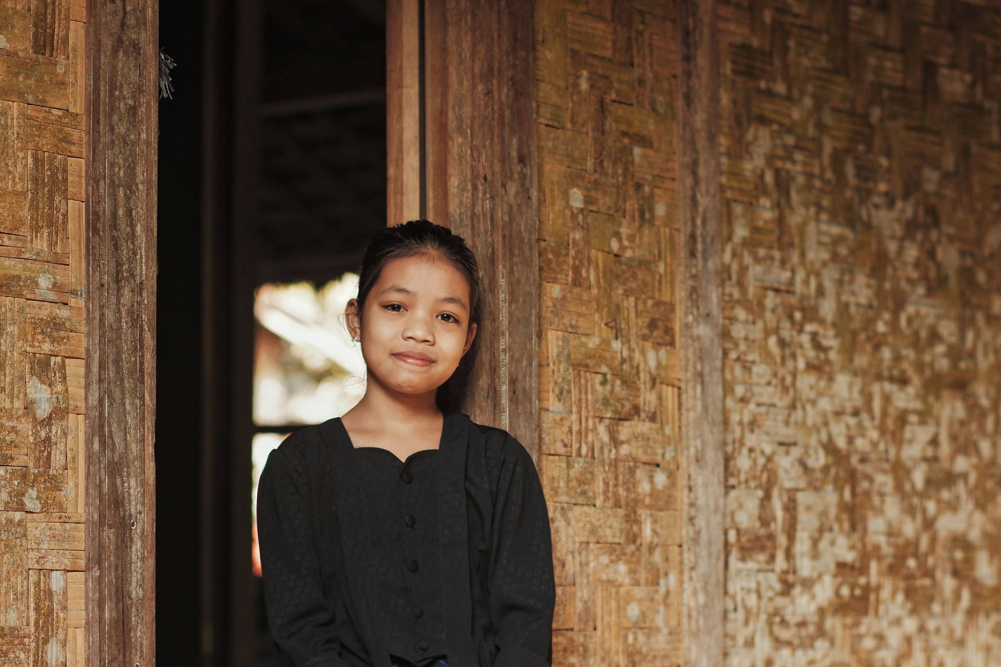 Young girl smiling while standing at a traditional doorway in Banten, Indonesia.