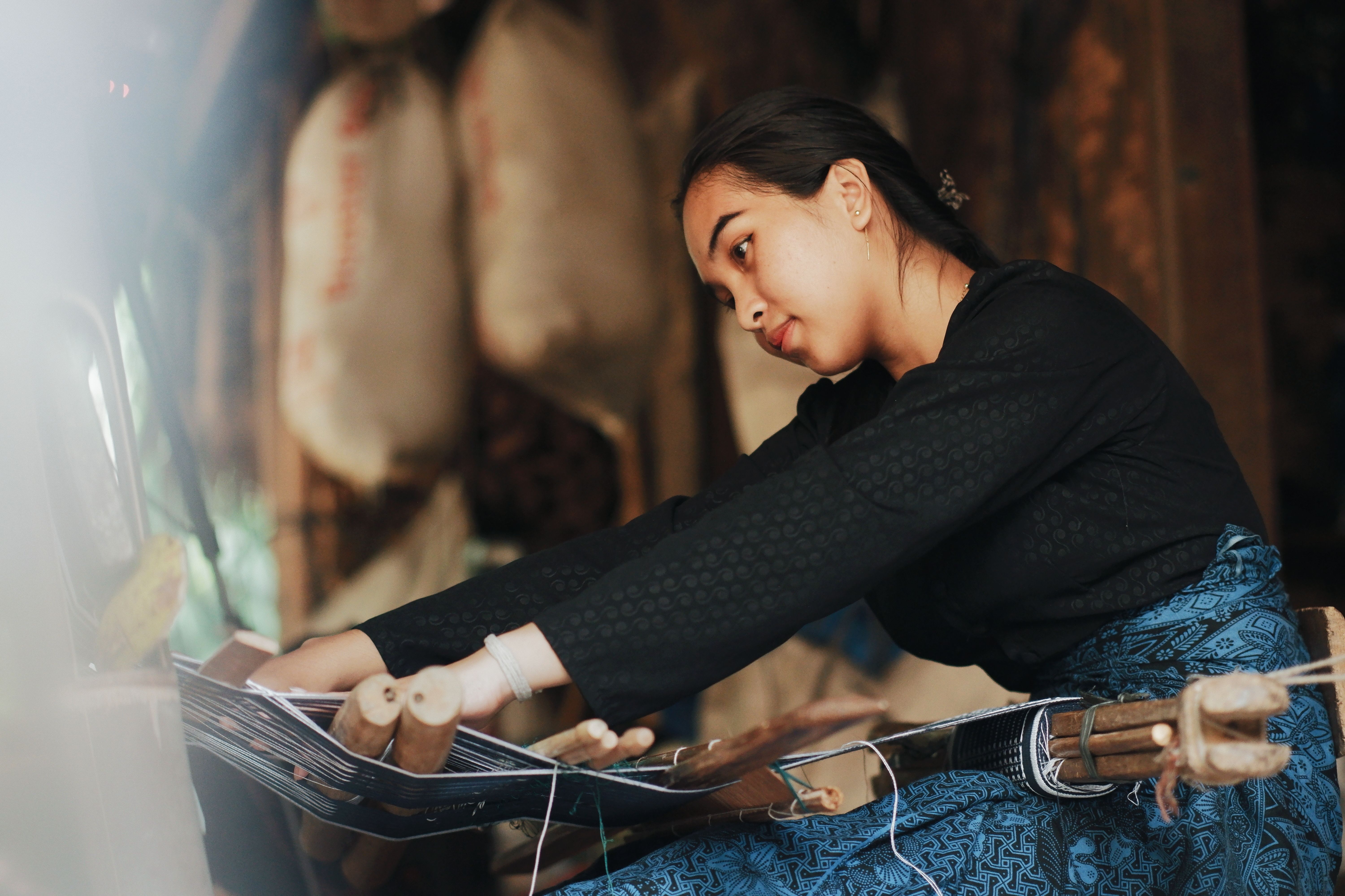 A woman skillfully weaving traditional fabric on a loom in Banten, Indonesia.