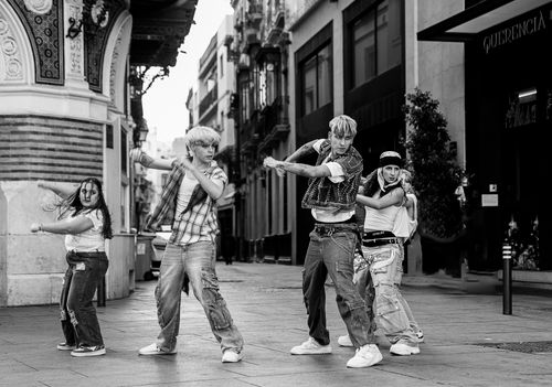 Free Four street dancers performing energetically in a historic street of Seville, Spain. Stock Photo
