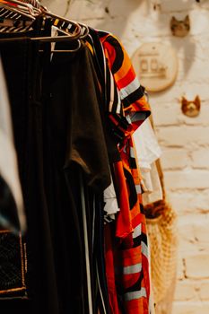 Colorful vintage clothing on rails set against a brick wall in a boutique setting.