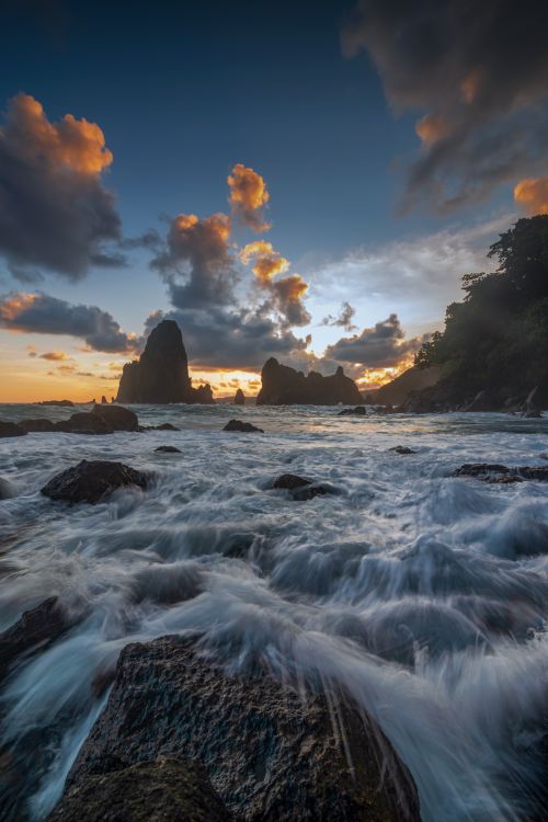 Free Stunning sunset over rocky waves and unique formations at Tanjung Papuma Beach, Jawa Timur, Indonesia. Stock Photo