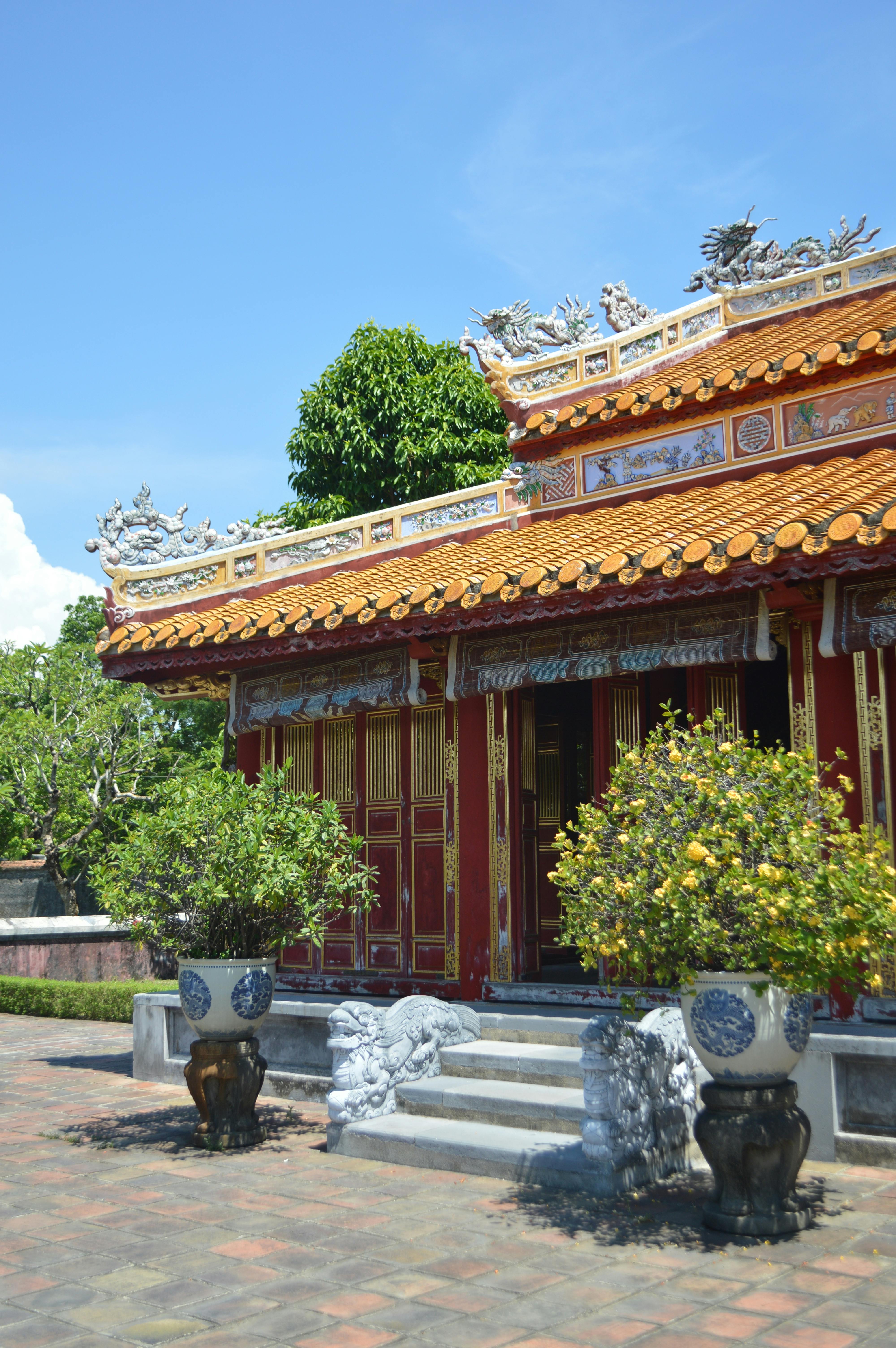 Explore a stunning Vietnamese temple with ornate decorations and lush greenery under a blue sky.