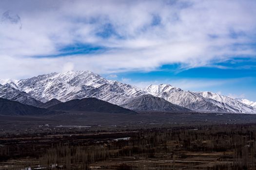 Majestic snow-capped mountains stretch under a vibrant blue sky, showcasing natural beauty.