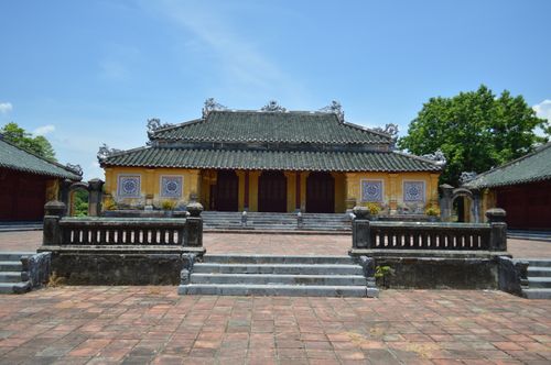 Free Historic Vietnamese structure featuring yellow walls and intricate roof design under a clear blue sky. Stock Photo