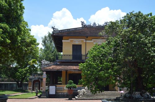 Free A traditional Asian building nestled among lush greenery under a bright blue sky. Stock Photo