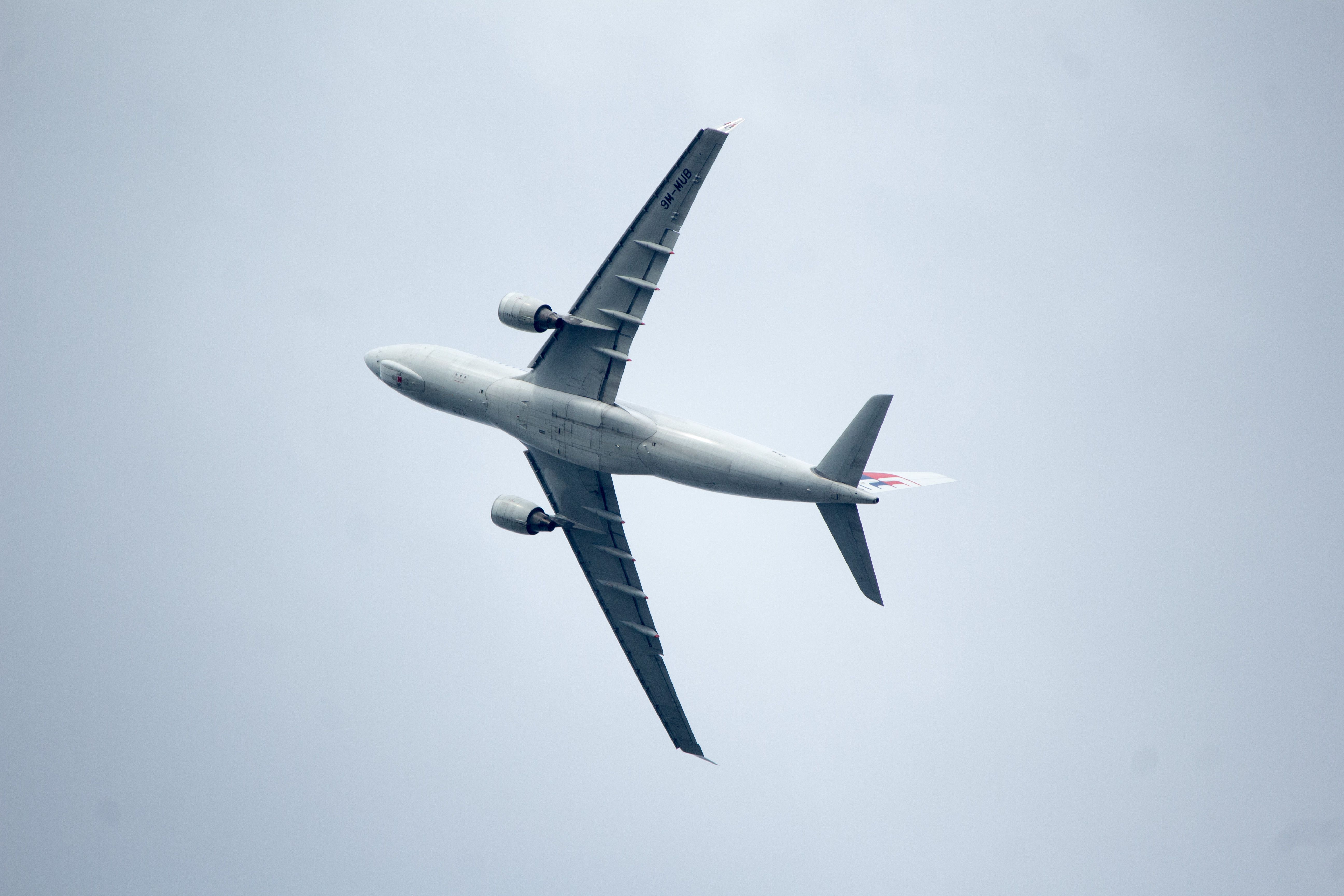 Commercial airplane mid-flight against a clear sky captured from below.