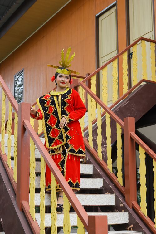 Free Woman in vibrant traditional Indonesian attire descending stairs outdoors. Stock Photo