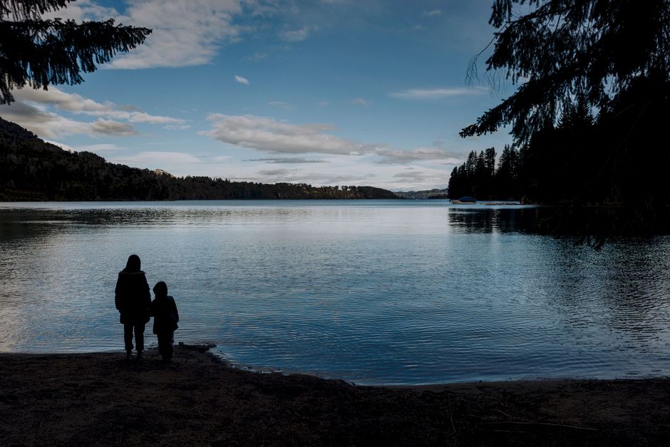 A serene view of a parent and child by a lake in San Carlos de Bariloche, Argentina.