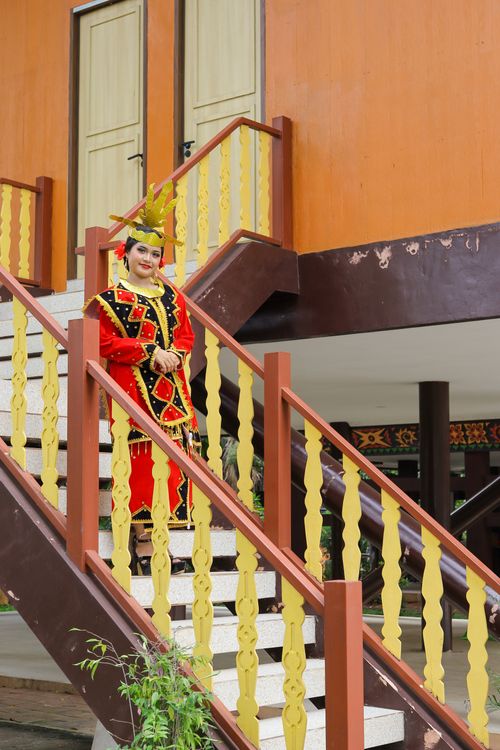 Free Person in Indonesian traditional dress standing on a stairway with colorful decor. Stock Photo