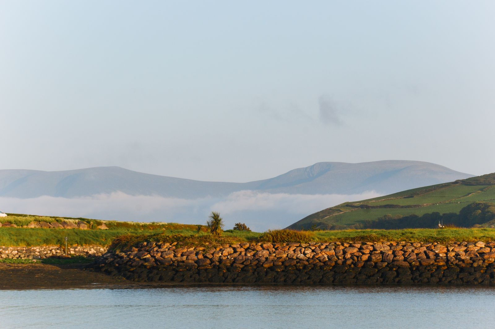 View of the Dingle Peninsula with mountains, sea, and greenery under a clear sky