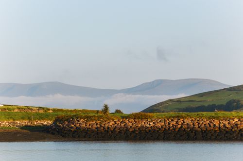 Free Tranquil view of the Dingle Peninsula with mountains, sea, and lush greenery under a clear sky. Stock Photo