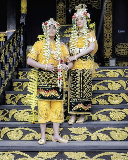 Free A couple in traditional Indonesian wedding attire poses on ornately decorated steps, showcasing cultural richness. Stock Photo
