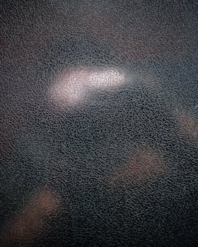 黑色皮革表面纹理的特写镜头，带有明显的裂缝图案，非常适合用作背景