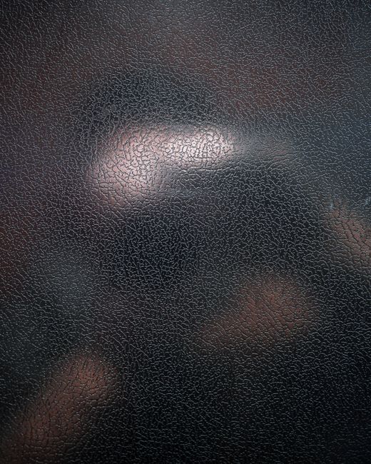 Close-up of a textured black leather surface with a distinct cracked pattern, perfect for backgrounds.