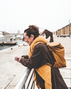 一位穿着时尚外套、背着背包的女子在马赛码头享受着阳光明媚的一天