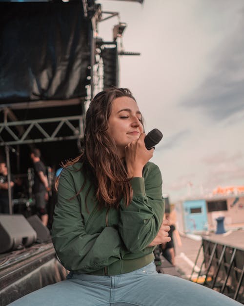 Woman In Green Jacket Holding A Microphone