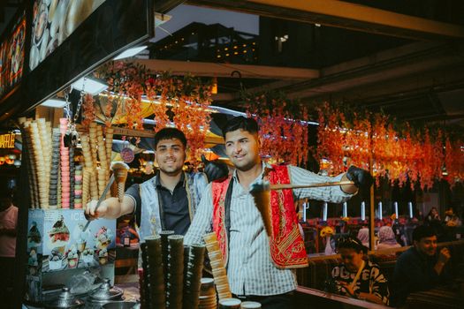 Two men in traditional attire selling ice cream at a lively night market.