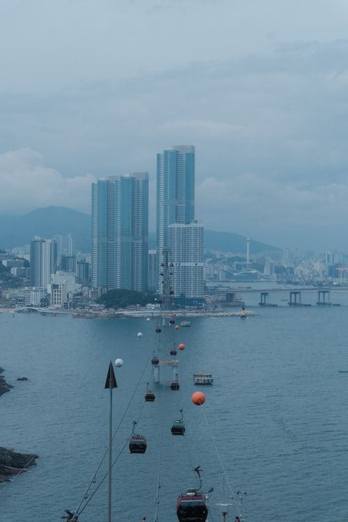 Free Dramatic view of cable cars crossing the ocean with Busan cityscape in the background. Stock Photo