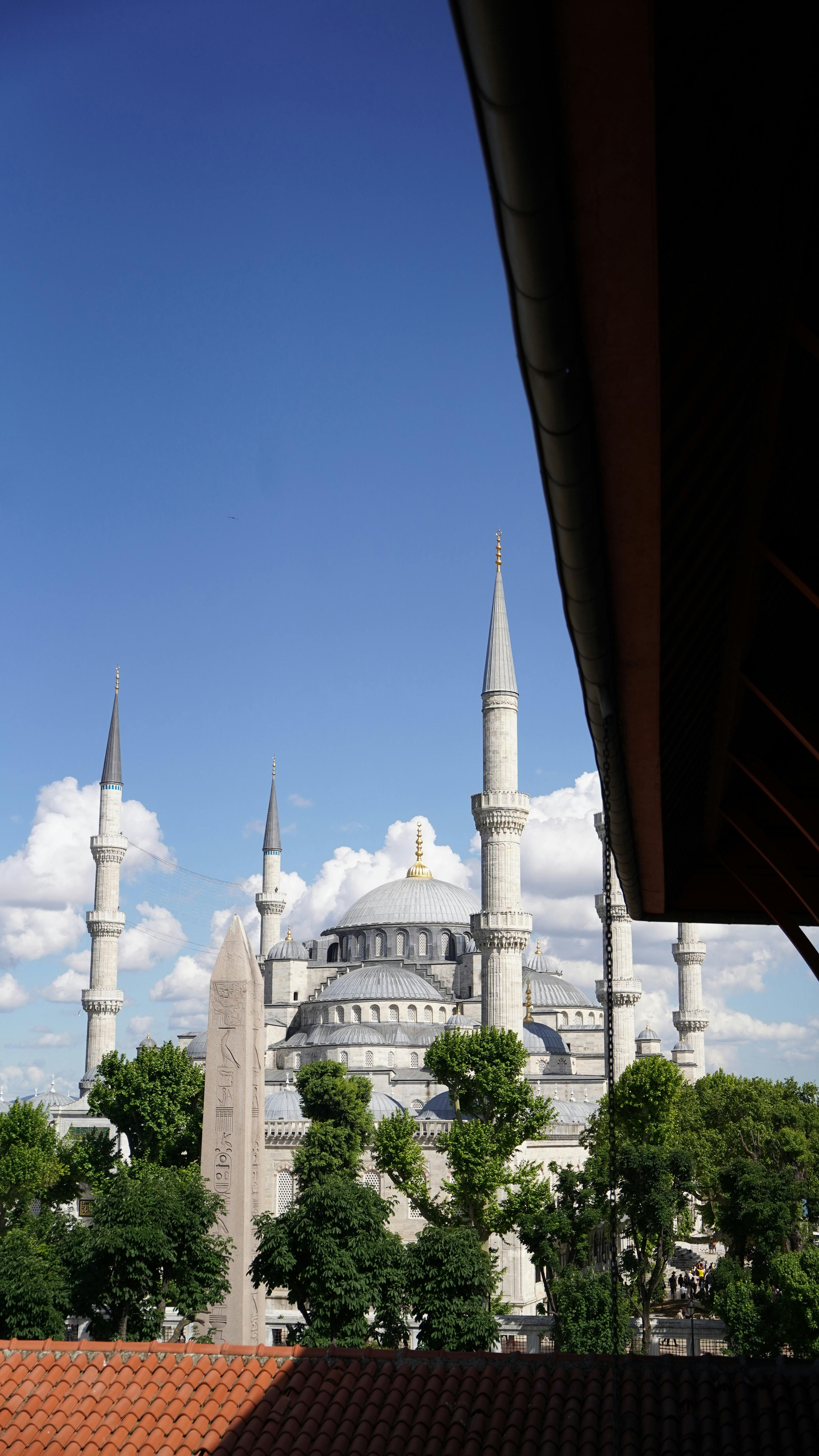 A stunning view of the Blue Mosque and ancient obelisk in Istanbul, framed by nearby architecture under a clear blue sky.