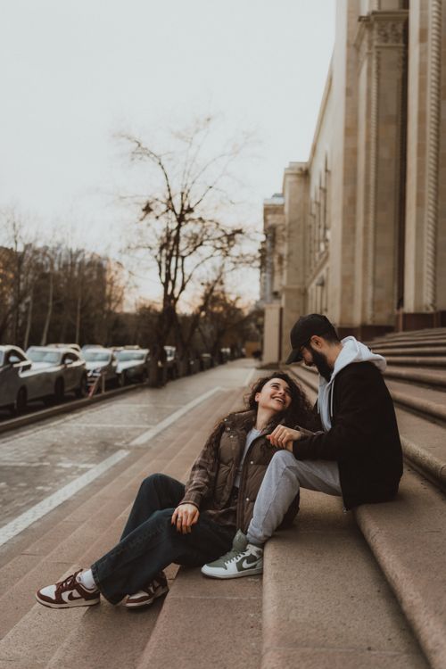 Free Young couple shares a tender moment on city steps during autumn. Urban romance captured. Stock Photo