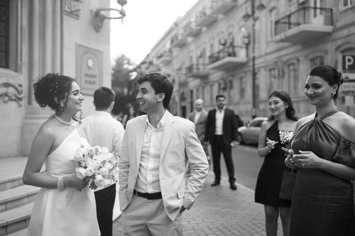 Free Black and white photo capturing a happy couple on their wedding day with guests on a city street. Stock Photo