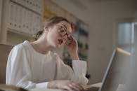 在现代办公环境中，一位戴着眼镜的女性正专注地使用笔记本电脑工作