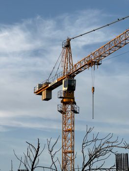 An industrial tower crane towering over a construction site with a clear blue sky background.
