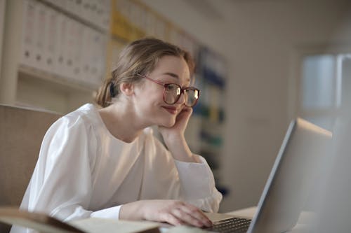 Женщина в белых с длинными рукавами, используя ноутбук