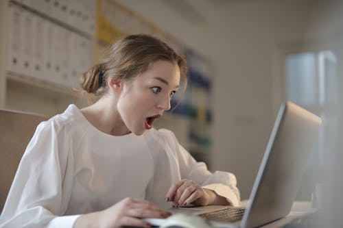 Free Woman in White Long Sleeve Shirt Using Silver Laptop Computer Stock Photo