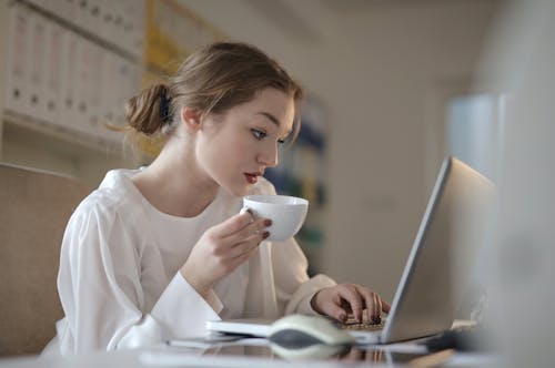 拿着杯子的白色长袖的妇女