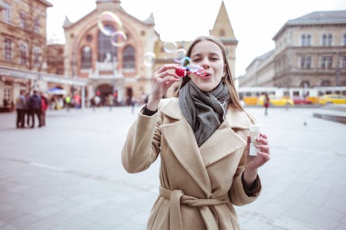 Woman in Brown Coat Blowing Bubbles