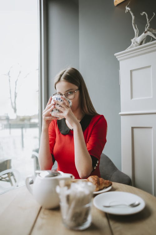 Free Woman In Red Long Sleeve Holding A Ceramic Mug Stock Photo
