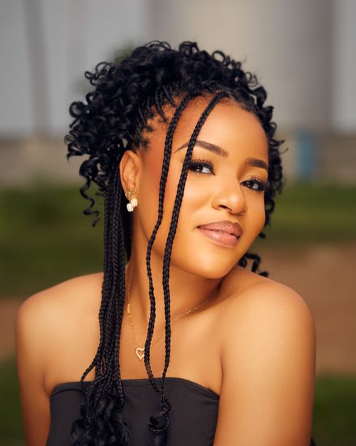 Free Elegant portrait of a woman with braided hair smiling in an outdoor setting. Stock Photo