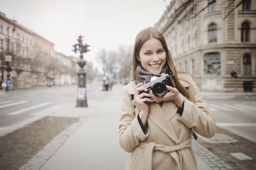 Woman In Brown Coat Holding Camera