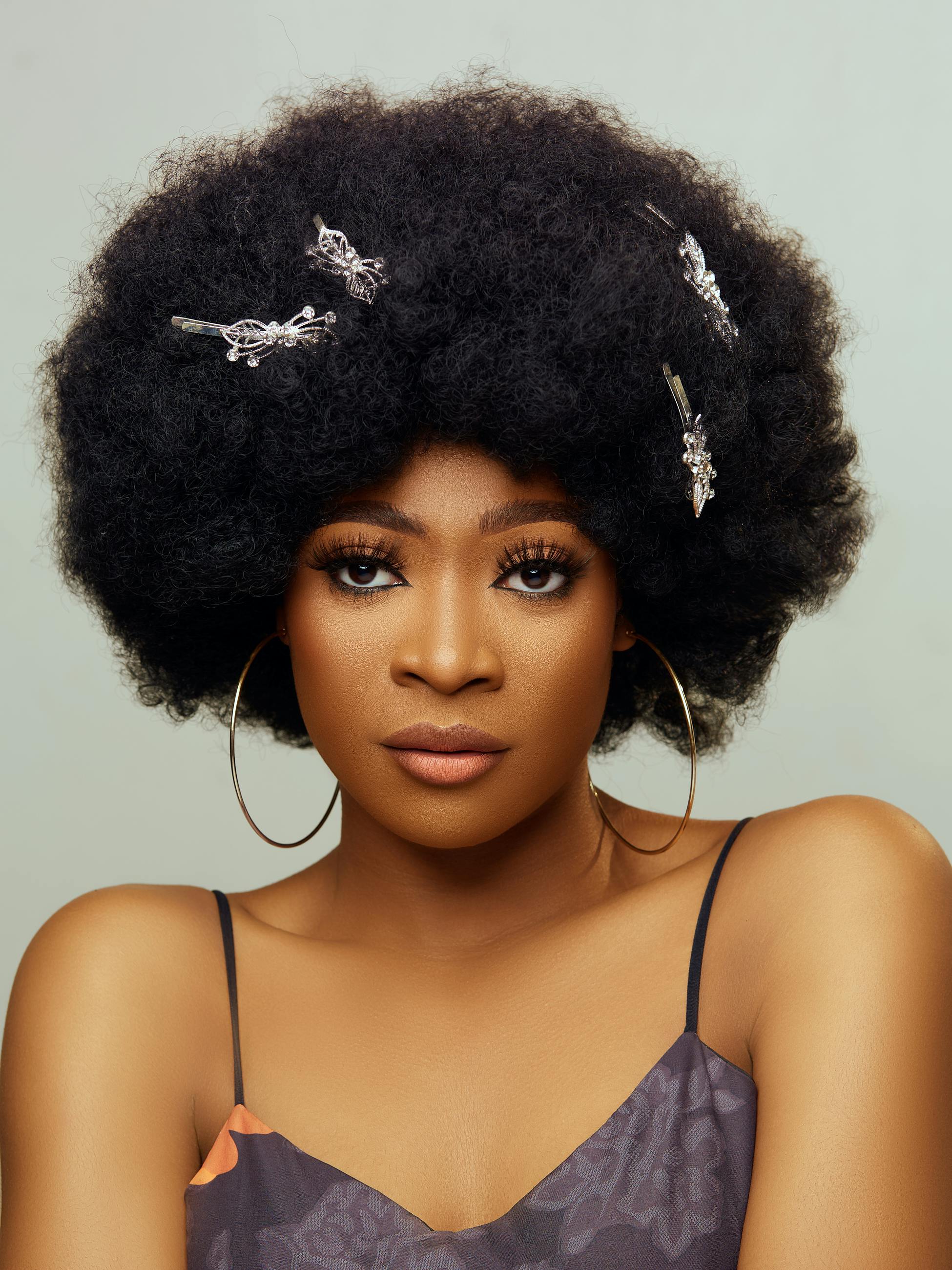 Stylish portrait of a woman with an afro hairstyle adorned with decorative pins.