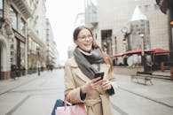 一位带着购物袋和智能手机的微笑女人在城市里享受冬日