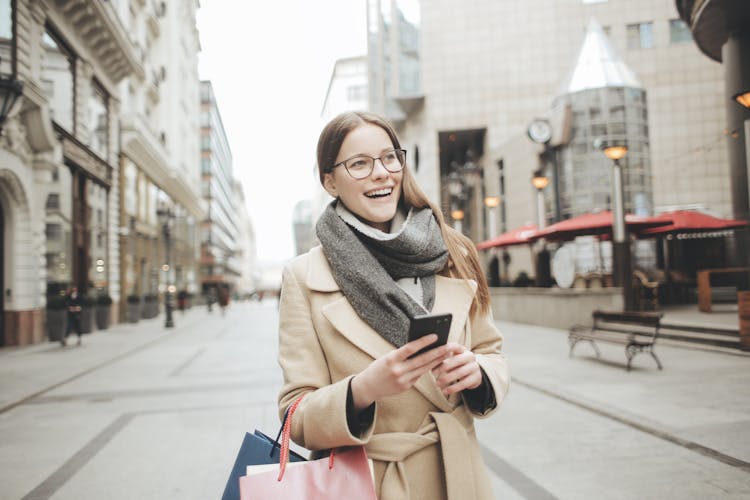 Woman In Brown Coat And Gray Scarf Holding Shopping Bags