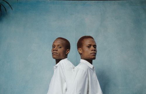 Free A creative portrait of two men in white shirts set against a blue background, exuding confidence. Stock Photo