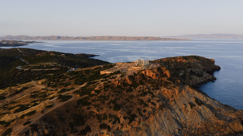Scenic sunset view of the Temple of Poseidon overlooking the Aegean Sea in Cape Sounion, Greece.