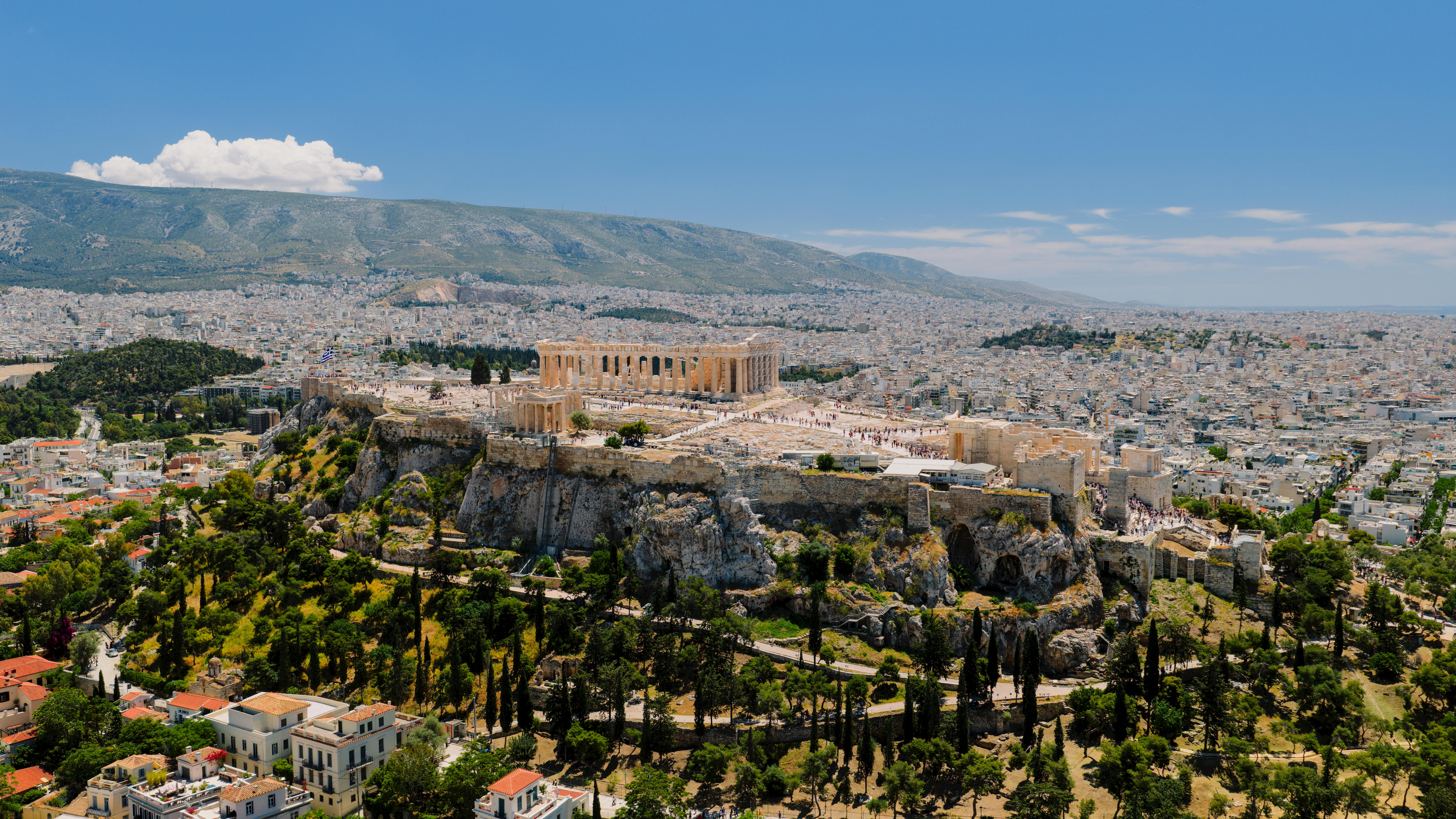 Stunning aerial shot of Athens' Acropolis surrounded by sprawling cityscape under a clear blue sky.