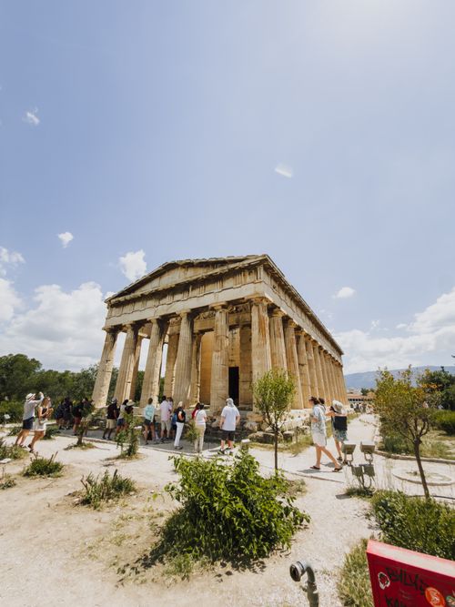 Free Tourists explore the ancient Temple of Hephaestus in Athens under a clear summer sky. Stock Photo