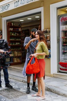 Street scene with filming crew and actors in Athens, Greece, capturing a vibrant market setting.
