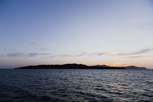 Stunning sunset view over the Aegean Sea with a distant silhouette of land near Fira, Greece.