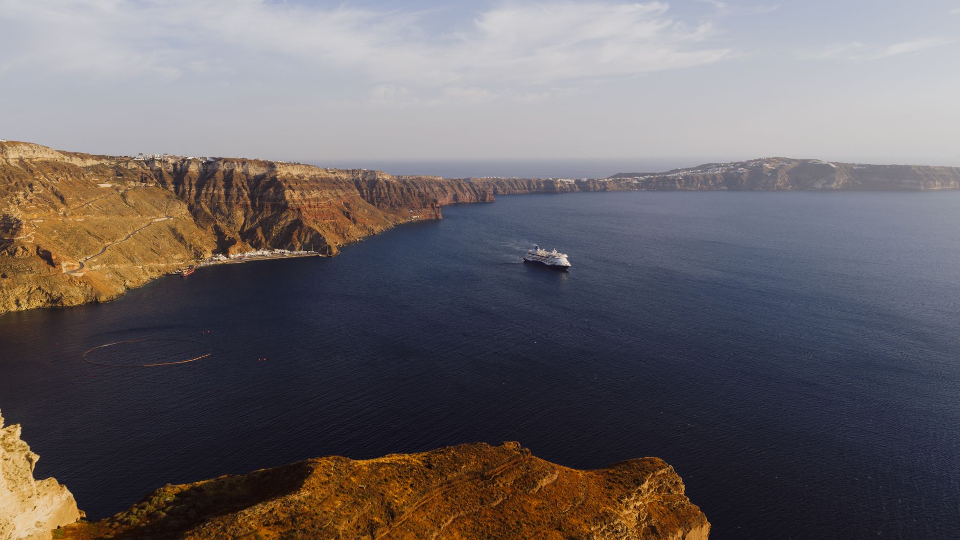 Cruise ship sailing below the cliffs of Fira in Santorini's caldera, a classic first Mediterranean cruise tender stop