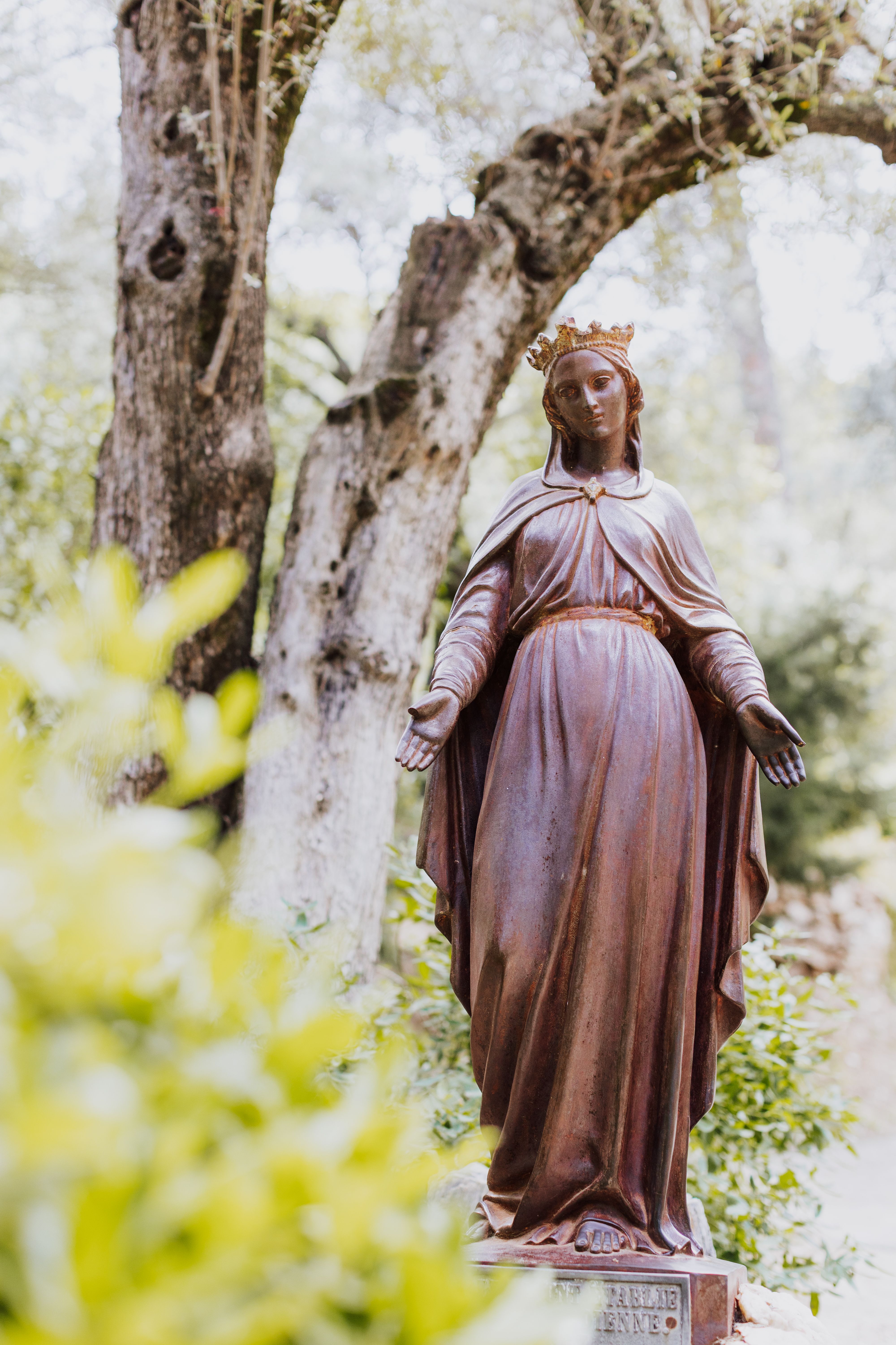 Statue of the Virgin Mary in a serene garden setting in İzmir, Türkiye.